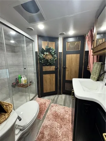 a bathroom with a granite countertop sink a toilet a mirror and shower