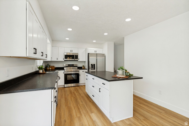 62 South Clark Lane Elk Ridge, UT 84651 - Photo 9 of 30 Kitchen featuring white cabinetry with black hardware, dark countertops, LVP flooring, recessed lighting, and stainless steel appliances