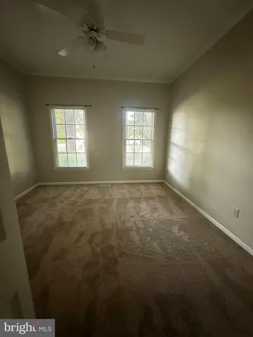 en empty room with windows and ceiling fan