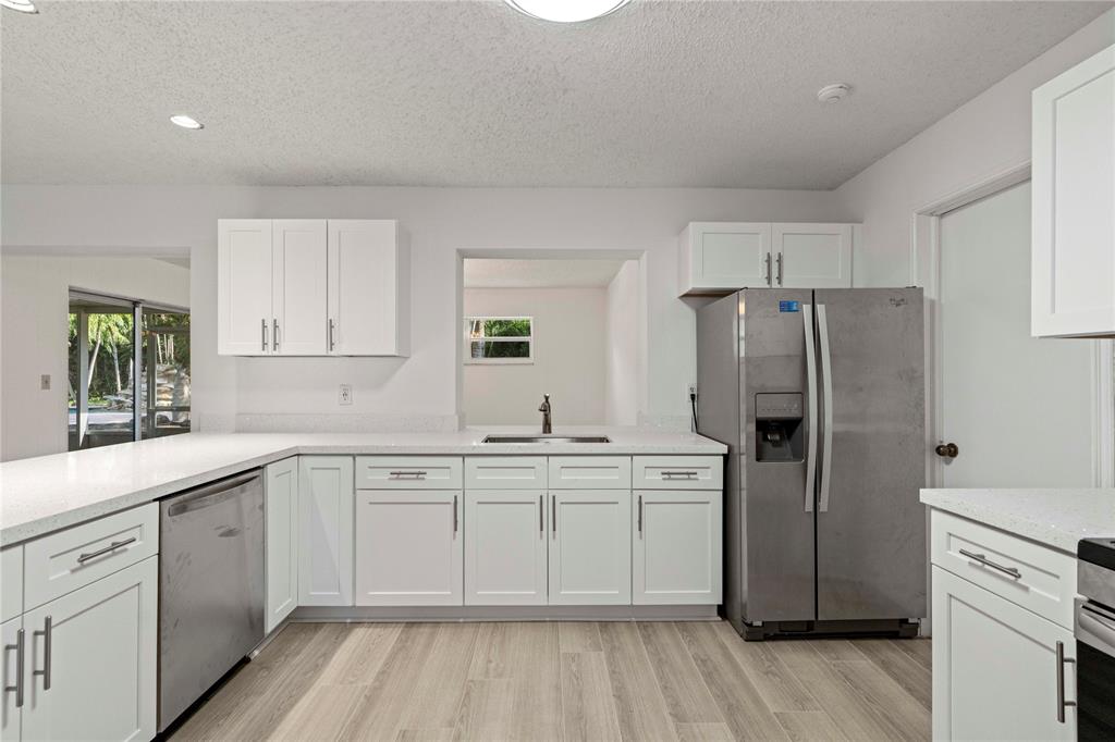 16900 Southwest 62nd Street Southwest Ranches, FL 33331 - Photo 19 of 48 a kitchen with a sink a refrigerator and white cabinets