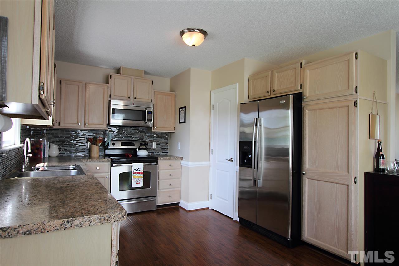 4213 Bluewing Road Raleigh, NC 27616 - Photo 8 of 16 a kitchen with granite countertop a refrigerator a stove a sink and a counter space
