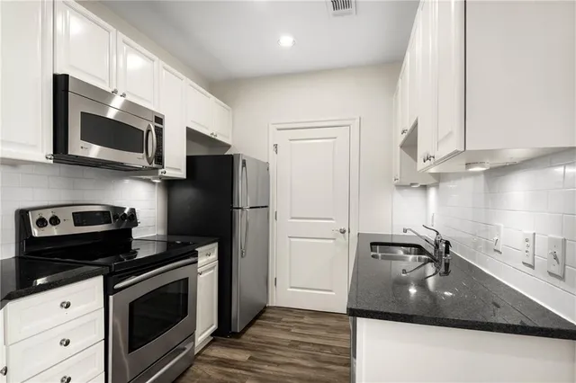 a kitchen with stainless steel appliances granite countertop a sink stove and microwave