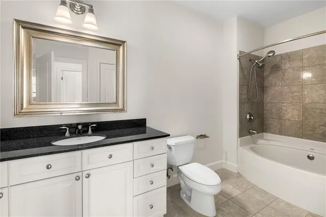 a bathroom with a granite countertop sink a toilet a mirror and bathtub