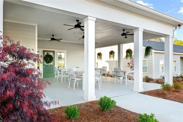 a view of a patio with table and chairs potted plants and floor to ceiling window