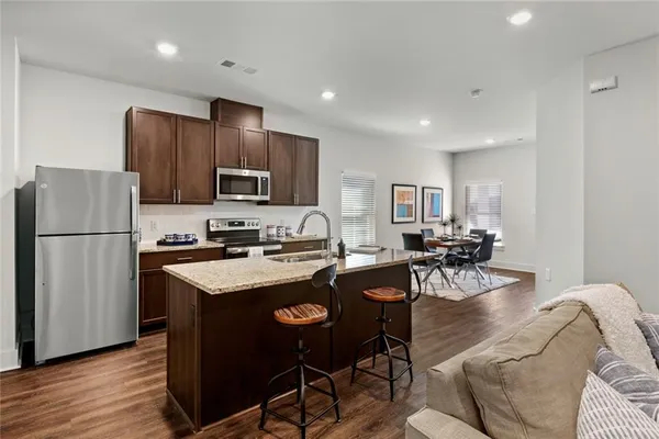 a kitchen with stainless steel appliances granite countertop a refrigerator a stove a sink a dining table and chairs