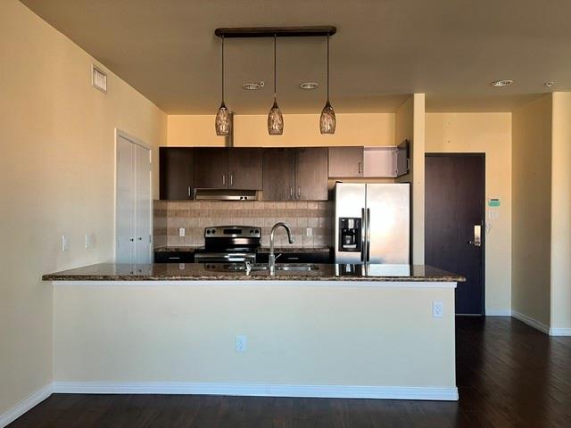 1100 West Trinity Mills Road, Unit 2001 Carrollton, TX 75006 - Photo 9 of 23 a kitchen with stainless steel appliances a sink a refrigerator and wooden cabinets