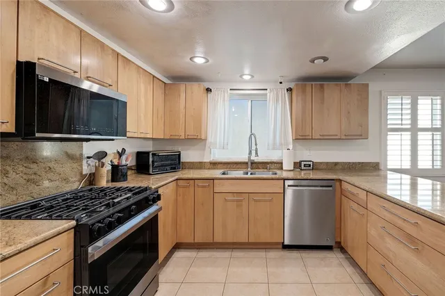 a kitchen with stainless steel appliances granite countertop a stove a sink and a microwave