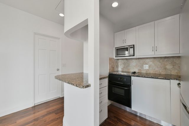 a kitchen with granite countertop white cabinets and black appliances