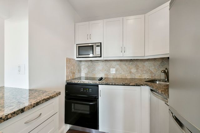 a kitchen with granite countertop white cabinets and stainless steel appliances