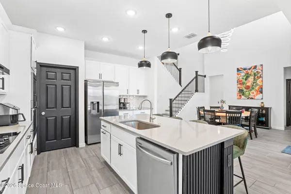 a kitchen with stainless steel appliances granite countertop a sink a stove a refrigerator and chairs