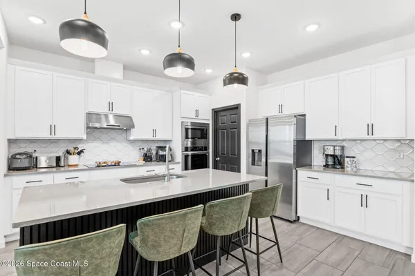 a kitchen with stainless steel appliances kitchen island granite countertop a sink a microwave a stove and white cabinets