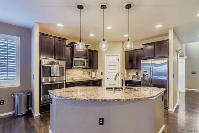 a kitchen with kitchen island a counter top space stainless steel appliances and wooden floor