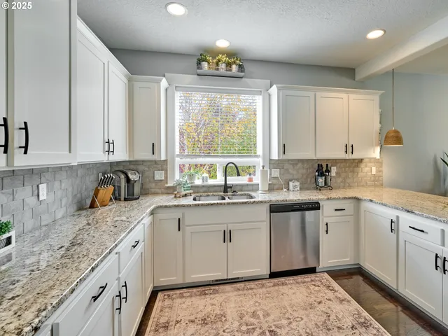 a kitchen with granite countertop a sink white cabinets and window