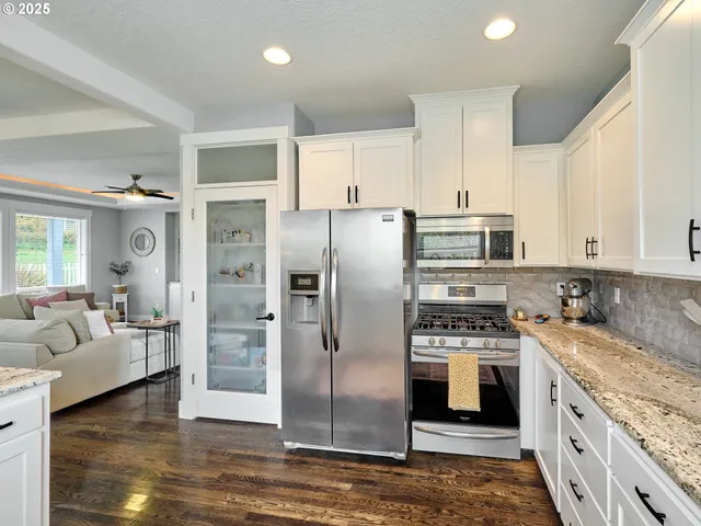 a kitchen with stainless steel appliances granite countertop a refrigerator a stove and white cabinets