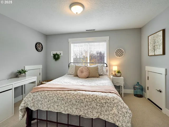 a bedroom with a bed and a lamp on dresser