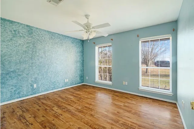 a view of an empty room with a window and wooden floor