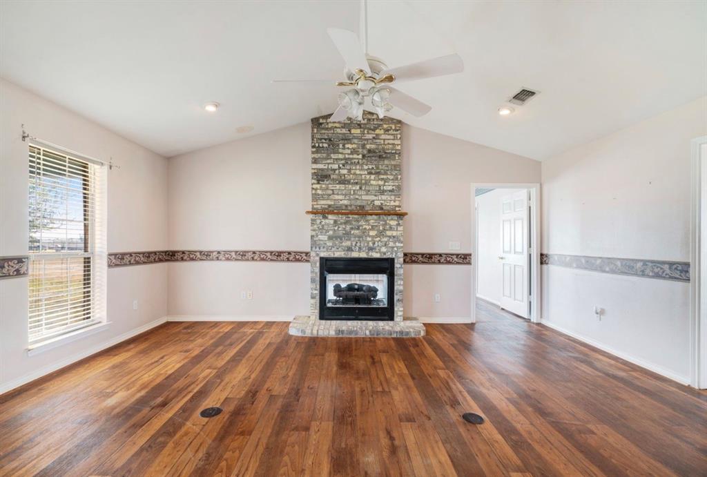 3754 County Road Paris, TX 75462 - Photo 5 of 33 an empty room with wooden floor fireplace and windows
