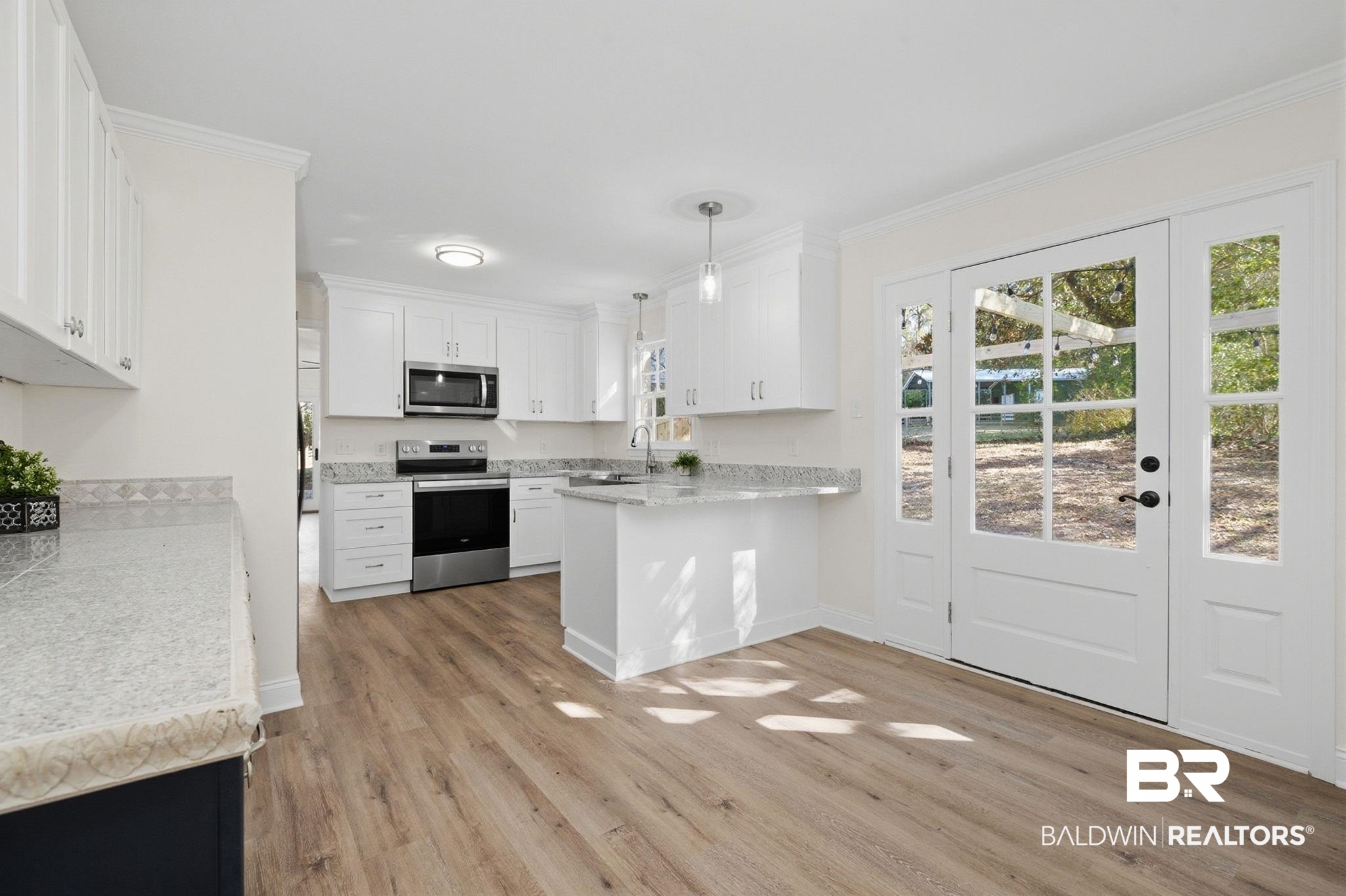 814 Nassau Drive Mobile, AL 36608 - Photo 5 of 44 Kitchen featuring hanging light fixtures, stainless steel appliances, white cabinetry, a peninsula, and light wood-type flooring