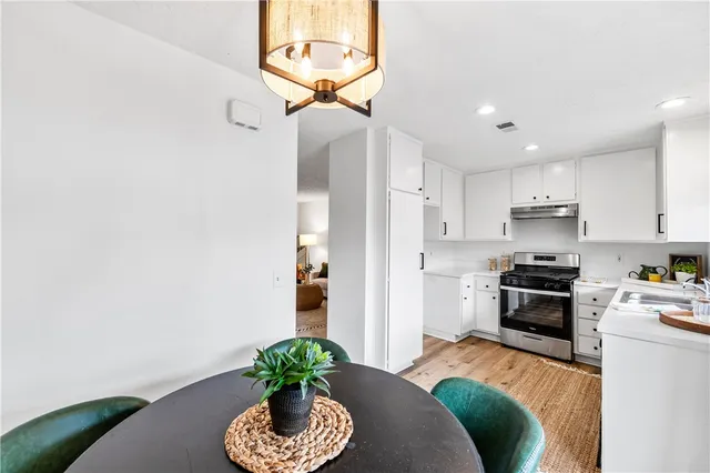 a kitchen with stainless steel appliances granite countertop a stove a sink dishwasher and a refrigerator with wooden floor