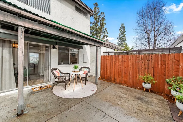 a view of a patio with table and chairs potted plants and floor to ceiling window