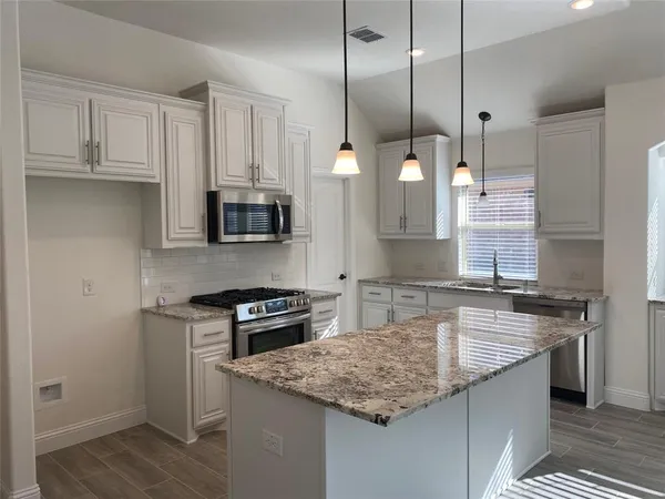 a kitchen with stainless steel appliances granite countertop a sink a stove and a wooden cabinets