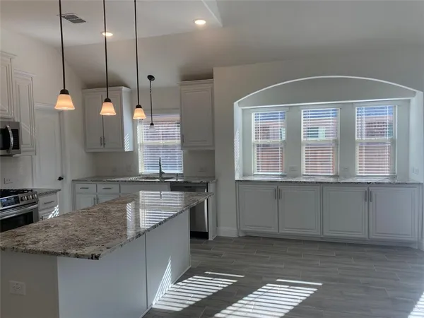 a kitchen with stainless steel appliances granite countertop a stove a sink and a microwave