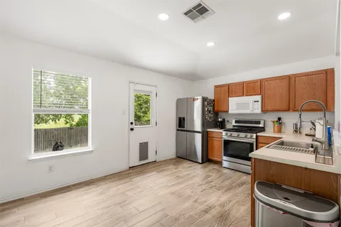 a kitchen with stainless steel appliances granite countertop a refrigerator a sink dishwasher a stove with wooden floors and cabinets