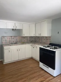a white kitchen with granite countertop stainless steel appliances a sink stove and cabinets