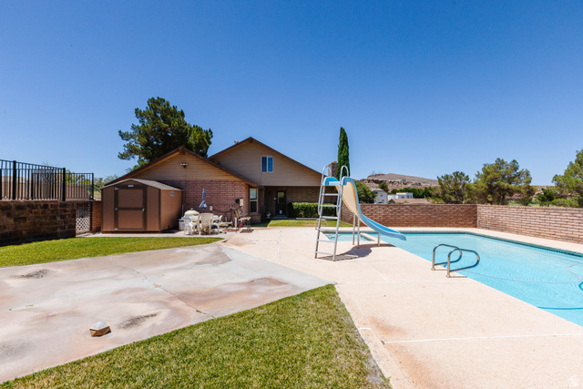 1470 Redwood Tree Street St. George, UT 84790 - Photo 51 of 53 Backyard featuring an inground swimming pool with a slide, a storage shed, and a brick-built perimeter wall