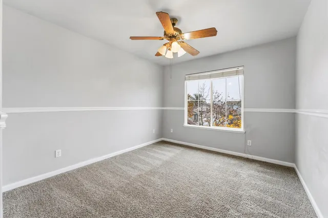 an empty room with window and ceiling fan
