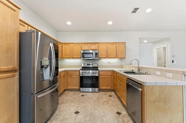 a kitchen with stainless steel appliances granite countertop a refrigerator sink and stove