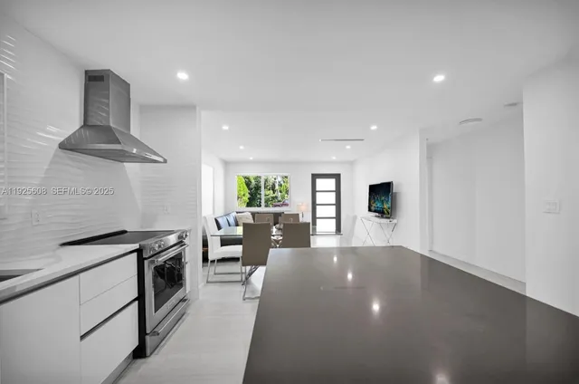 a kitchen with stainless steel appliances a stove a chimney a sink and a refrigerator