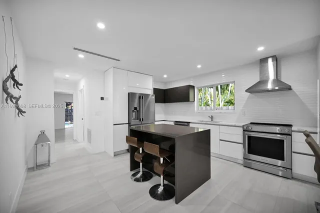 a kitchen with kitchen island a stove a sink a refrigerator and a oven with wooden floor