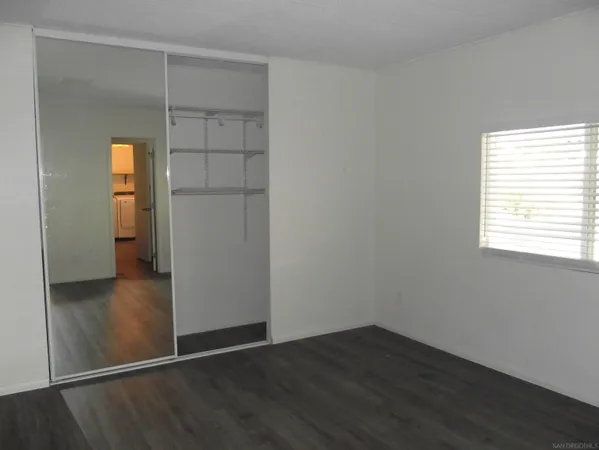 an empty room with wooden floor cabinet and closet