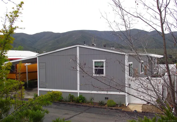 a view of a house with a yard and mountain view in back