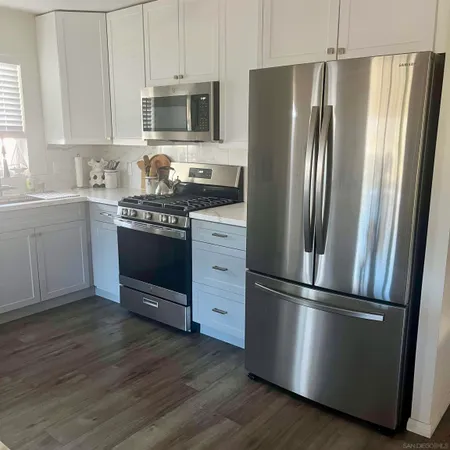 a kitchen with stainless steel appliances granite countertop a refrigerator microwave and sink