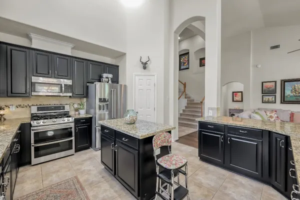 a kitchen with stainless steel appliances granite countertop a stove a sink dishwasher a refrigerator and a oven with wooden floor