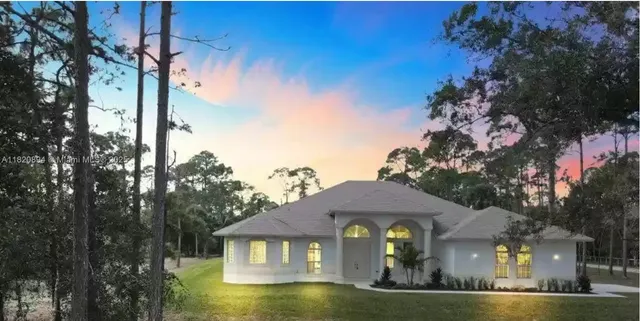 a view of a white house with a swimming pool and wooden fence