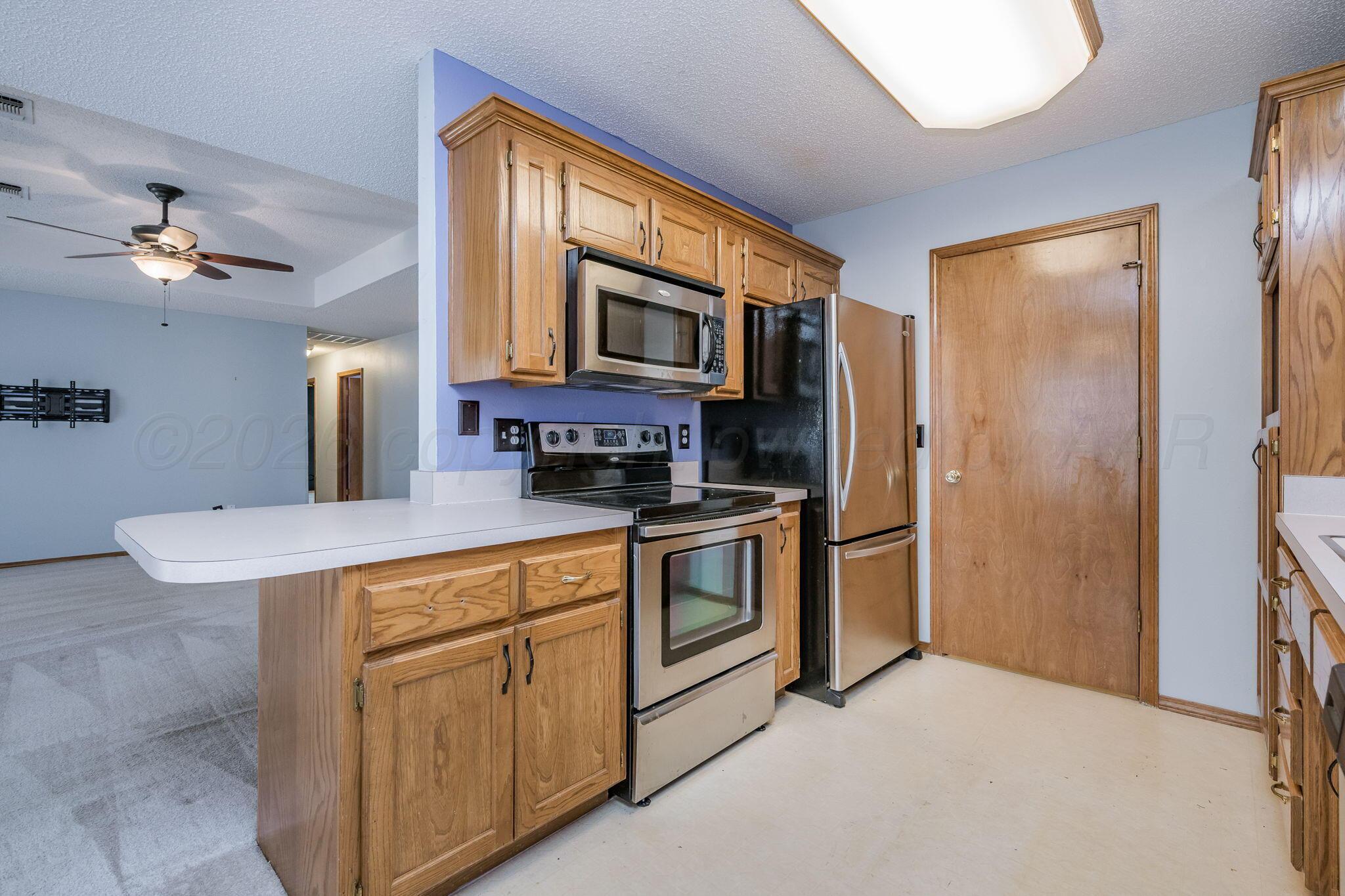 2904 Laguna Drive Amarillo, TX 79110 - Photo 5 of 17 a kitchen with stainless steel appliances granite countertop a refrigerator a stove a sink dishwasher and a microwave oven