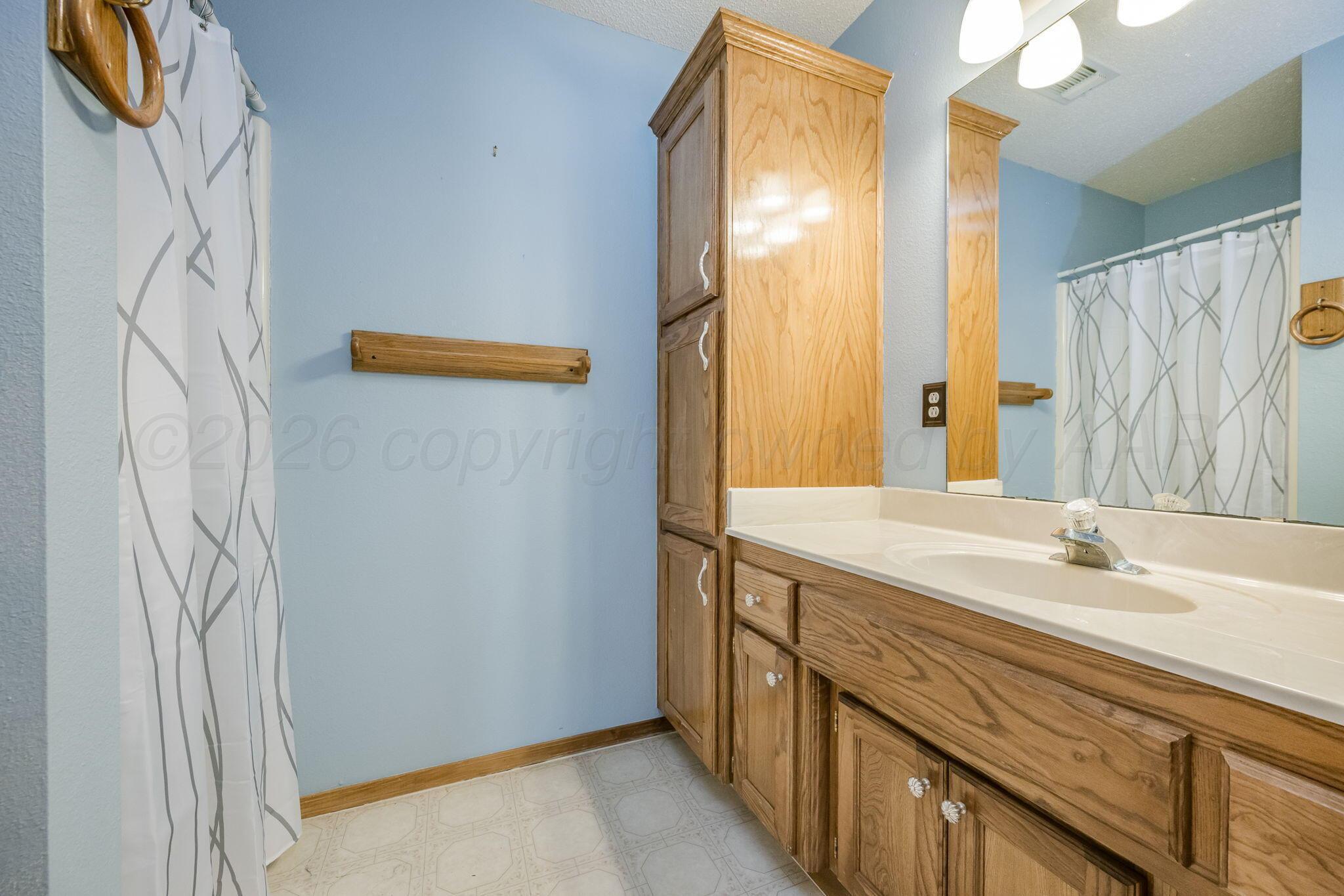 2904 Laguna Drive Amarillo, TX 79110 - Photo 10 of 17 a bathroom with a sink a mirror and a shower