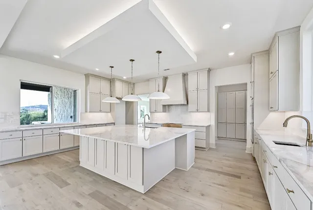 a large kitchen with kitchen island a sink a stove a refrigerator and white cabinets