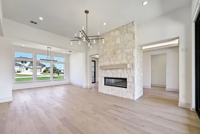 an empty room with wooden floor fireplace and windows