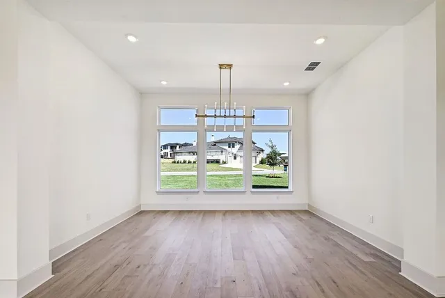 an empty room with wooden floor and outdoor view