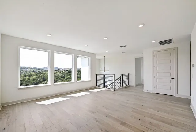 an empty room with wooden floor and windows