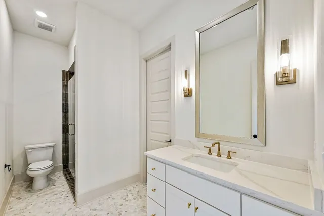 a bathroom with a granite countertop sink a toilet and a mirror
