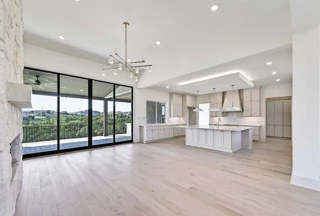 a view of large kitchen with kitchen island wooden floor and stainless steel appliances