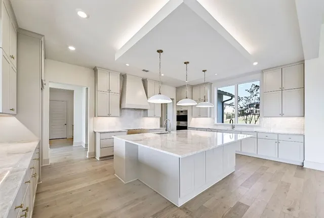a large white kitchen with kitchen island a sink a stove a refrigerator and white cabinets