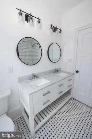 a bathroom with a double vanity sink mirror and toilet