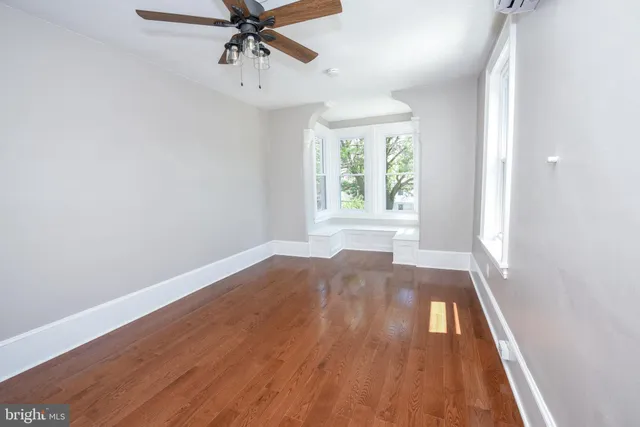 an empty room with wooden floor fan and windows
