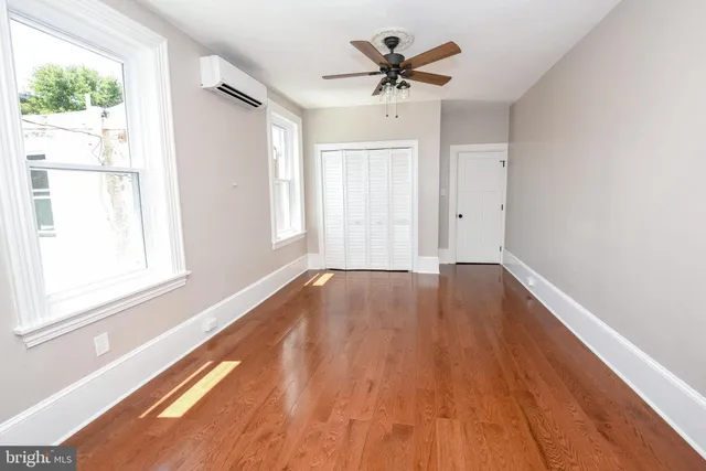 a view of empty room with wooden floor and fan